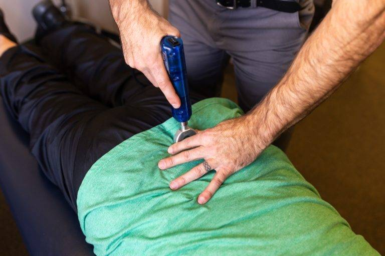 Instrument assisted adjustment performed by chiropractor on patient