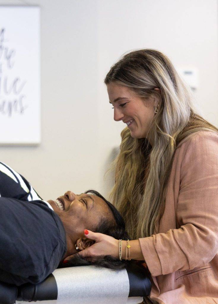 Dr. Chandler Gregory performing a chiropractic adjustment for neck pain on a female patient at our University location in Charlotte, North Carolina