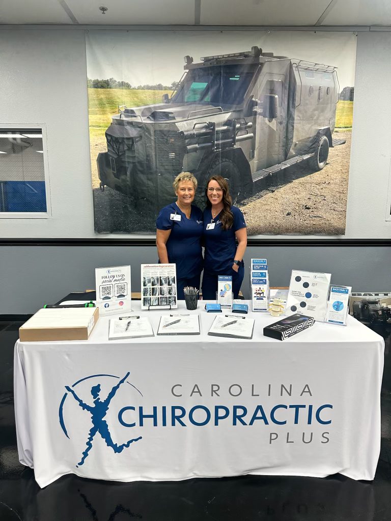 Our Carolina Chiropractic Plus team standing behind a table at a local event